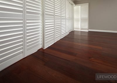 Jarrah flooring in Perth home with white venetian blinds